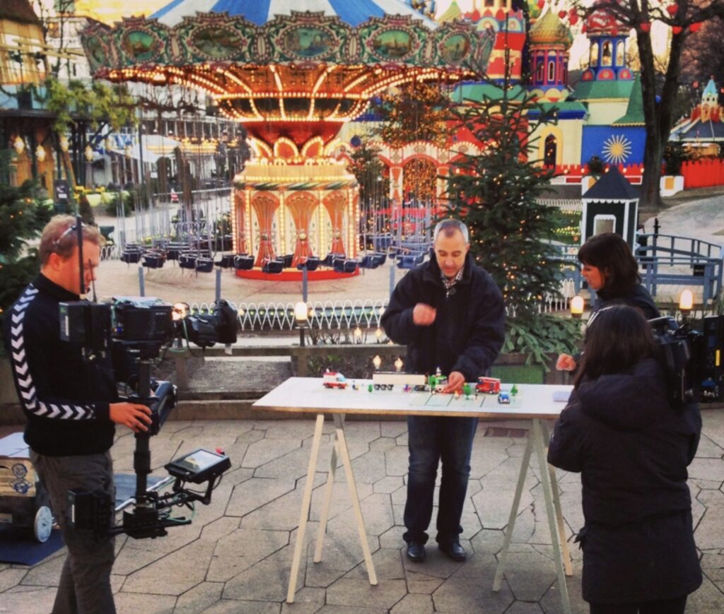 Erik Micheelsen explaining right-turn innovation with toy lorries to a TV2 Go'morgen Danmark crew in Tivoli, 2013